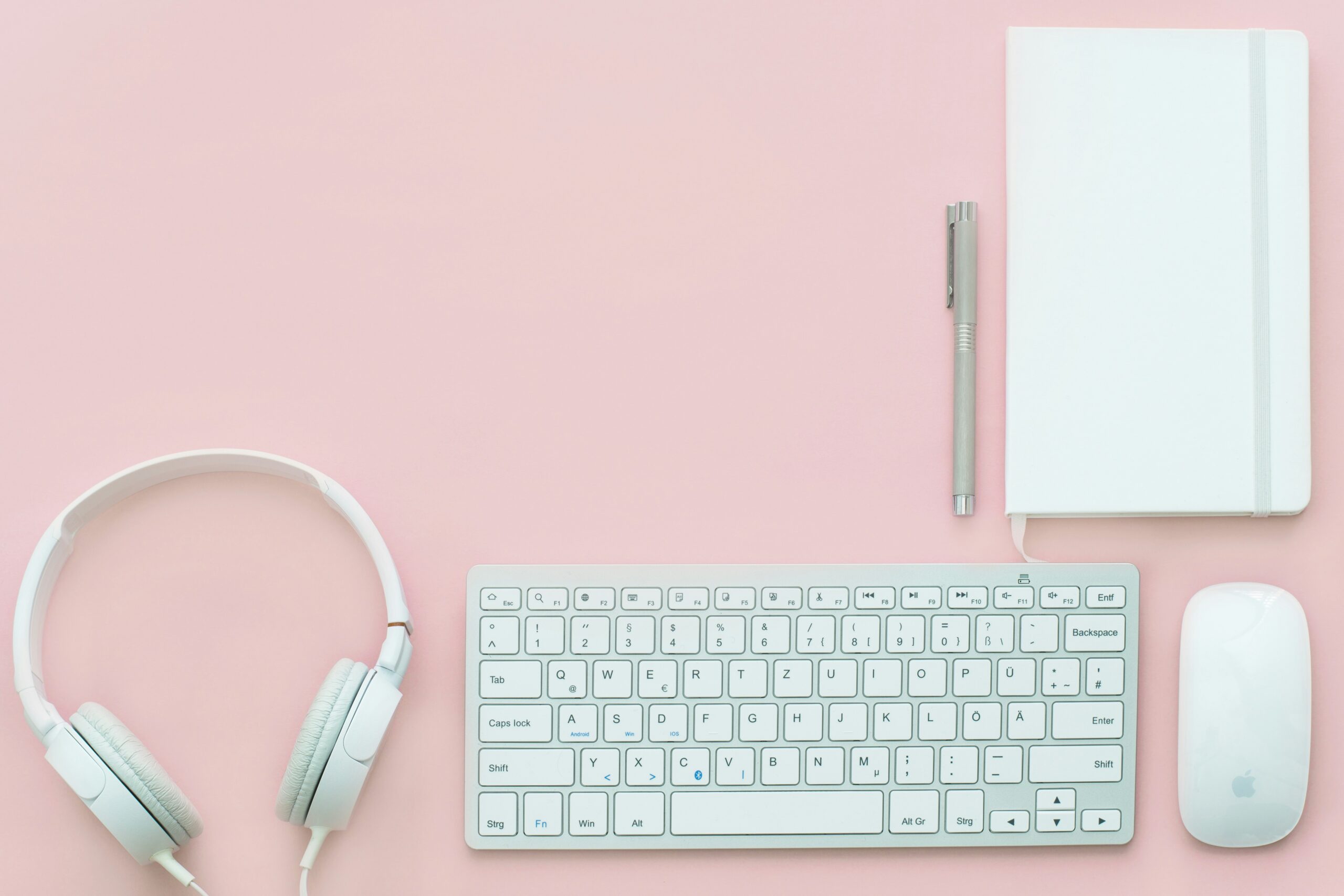 white Apple Magic Mouse beside of Magic Keyboard and headphones