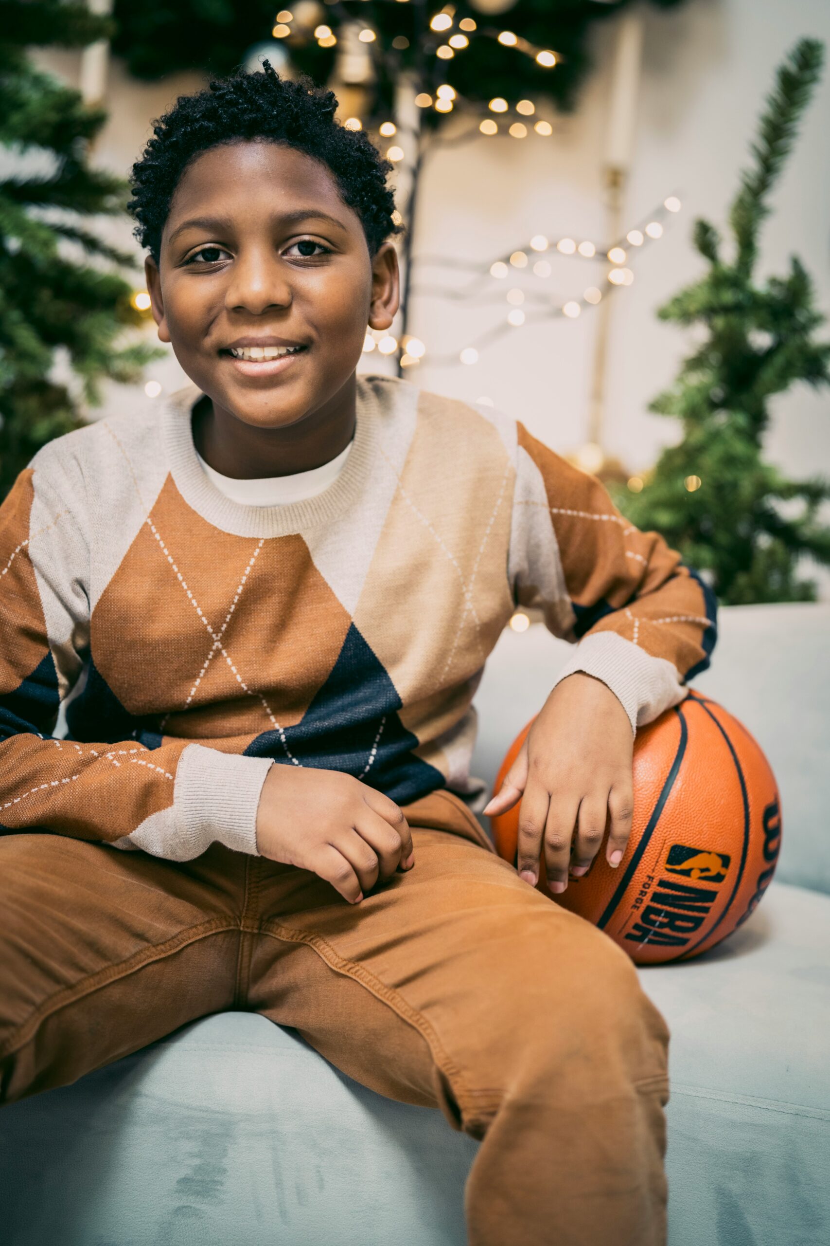 a young boy sitting on a couch holding a basketball