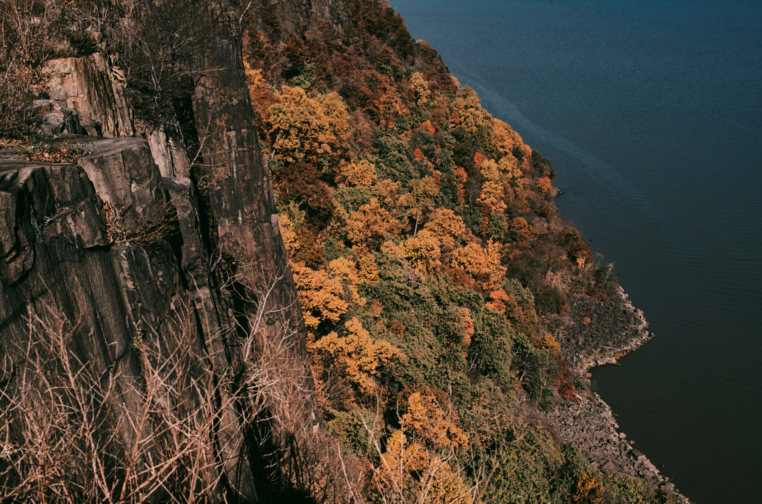 brown and green mountain beside blue sea during daytime